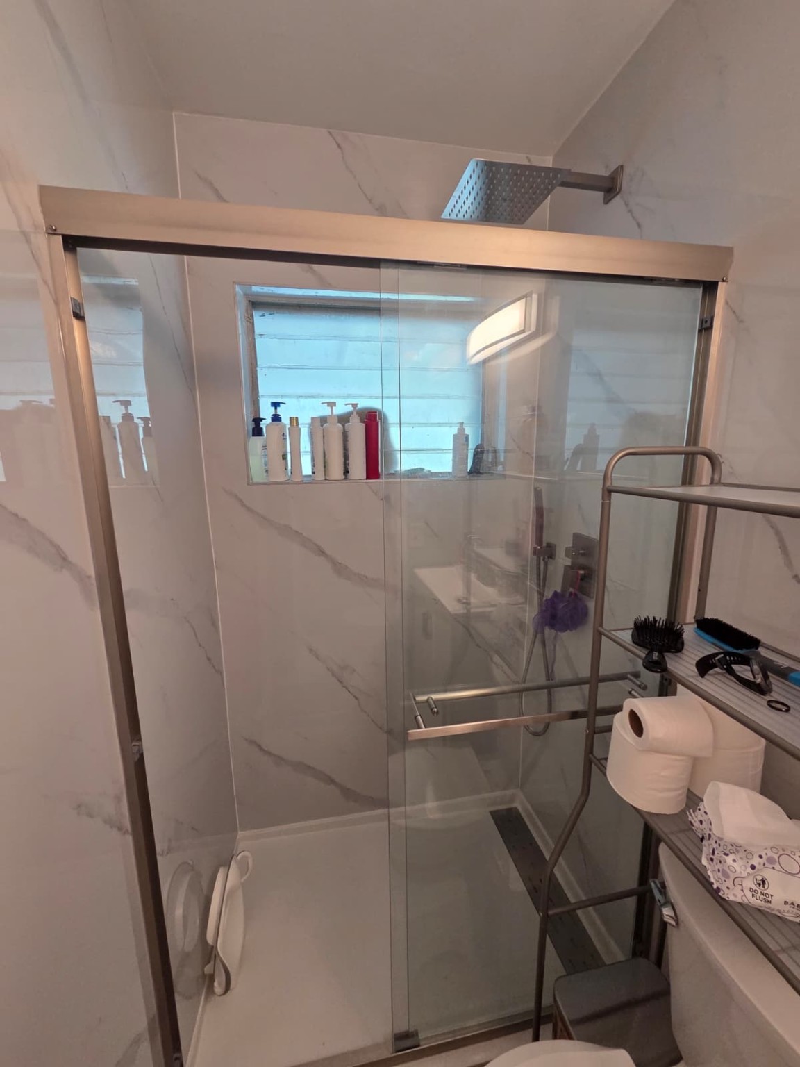 Completed shower-to-shower remodel with marble-look walls and glass enclosure